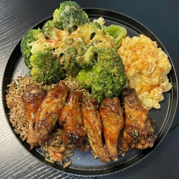 A plate of glazed chicken wings, rice, cheesy broccoli, and macaroni and cheese.